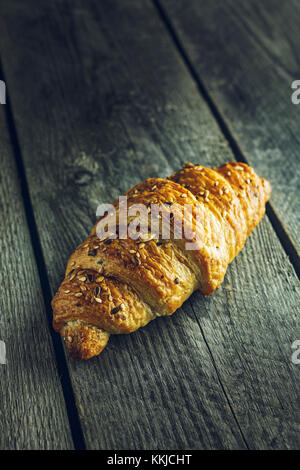 Crispy buttery croissants with seeds on old wooden table Stock Photo
