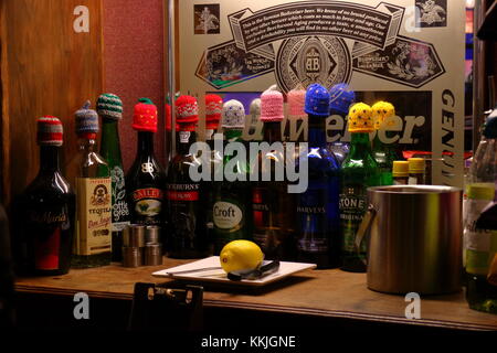 Liqueur and sherry bottles with Christmas woollen hats on their tops, on a bar in Devon, December 2017, England UK Stock Photo