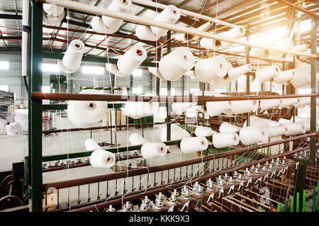 Textile industry - yarn spools on spinning machine in a textile factory Stock Photo