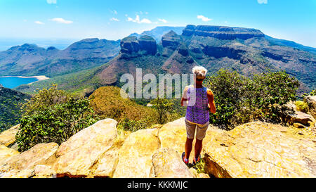 Senior woman enjoying the view of the Blyde River Canyon and Blyde River Dam from the viewpoint at the Three Rondavels in Mpumalanga, South Africa Stock Photo