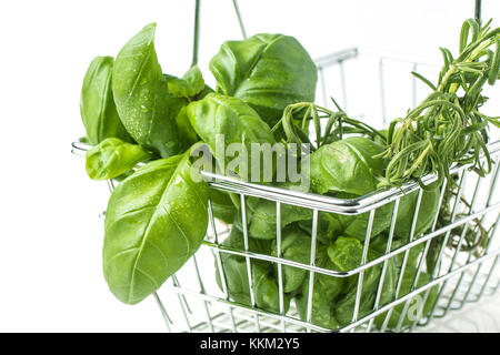 Metal food basket full of fresh herbs basil and rosemary over white Stock Photo