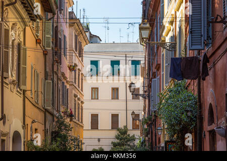 A back street in Rome, Italy, during summer looking at the walls of residential buildings above the streets filled with tourists below, washing lines  Stock Photo