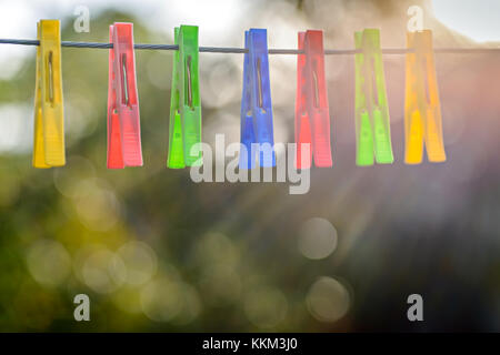Colorful pegs hanging on clothesline Stock Photo