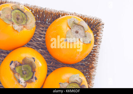 Fresh natural kaki fruits in the basket on white background Stock Photo