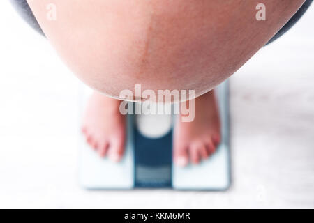 Pregnant woman standing on scales Stock Photo