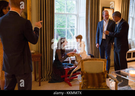 President Barack Obama talks with the Duke of Cambridge while the Duchess of Cambridge plays with Prince George; at left First Lady Michelle Obama talks with Prince Henry of Wales, at Kensington Palace in London April 22, 2016. (Official White House Photo by Pete Souza) Stock Photo