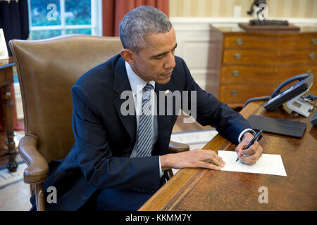 President Barack Obama signs a letter to a Cuban letter writer, in the Oval Office, March 14, 2016. (Official White House Photo by Pete Souza)  This official White House photograph is being made available only for publication by news organizations and/or for personal use printing by the subject(s) of the photograph. The photograph may not be manipulated in any way and may not be used in commercial or political materials, advertisements, emails, products, promotions that in any way suggests approval or endorsement of the President, the First Family, or the White House. Stock Photo