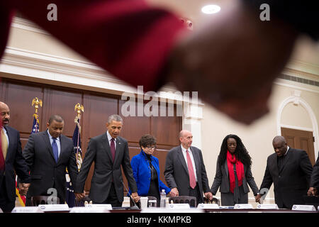 President Barack Obama joins hands with Transportation Secretary Anthony Foxx and Senior Advisor Valerie Jarrett during a prayer with African American faith and civil rights leaders prior to a meeting in the Eisenhower Executive Office Building of the White House, Feb. 26, 2015. (Official White House Photo by Pete Souza)  This official White House photograph is being made available only for publication by news organizations and/or for personal use printing by the subject(s) of the photograph. The photograph may not be manipulated in any way and may not be used in commercial or political materi Stock Photo