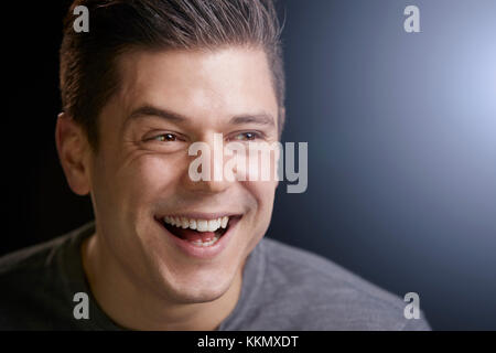 Portrait of a smiling young white man on black background Stock Photo