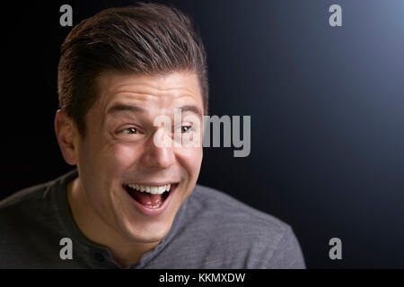 Portrait of a laughing young white man on black background Stock Photo