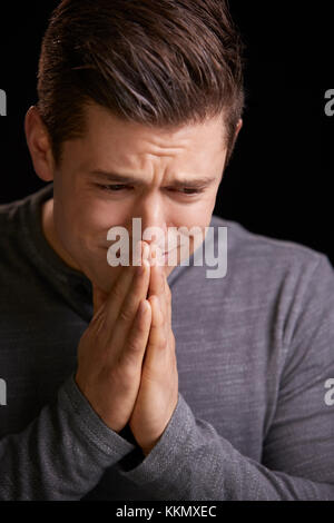 Worried young man with hands clasped, vertical portrait Stock Photo