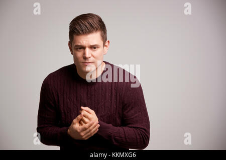 Nervous young white man rubbing his hands looking away Stock Photo
