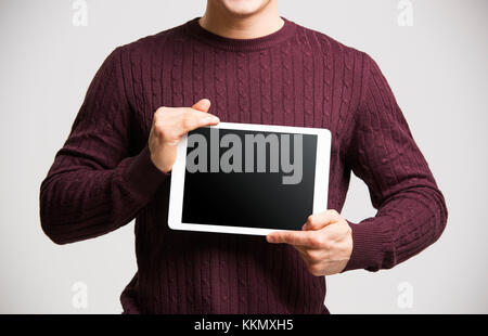Young man holds a tablet, showing its screen, mid section Stock Photo