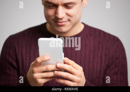 Close up of smiling young white man using a smartphone Stock Photo