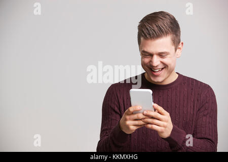 Portrait of a laughing young white man using a smartphone Stock Photo