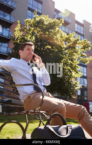 Businessman Talking On Mobile Phone During Lunch Break In Park Stock Photo