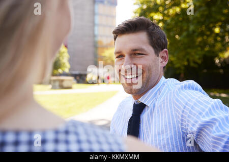 Businessman Talking To Female Colleague On Break In Park Stock Photo