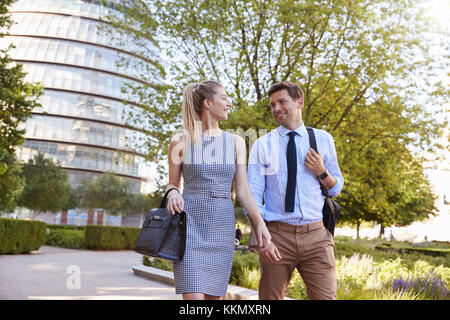Businessman And Businesswoman Walk to Work Through City Park Stock Photo