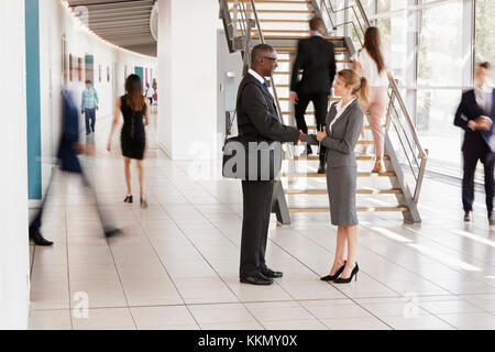 Businessman and woman shaking hands in a modern building Stock Photo