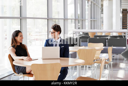 Businesswoman and businessman talking, laptop on table Stock Photo