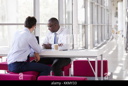 Two businessman look at laptop screen during a meeting Stock Photo