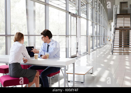 Businesswoman and businessman at a meeting looking at laptop Stock Photo