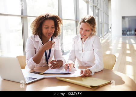 Two businesswomen discussing project, looking down Stock Photo