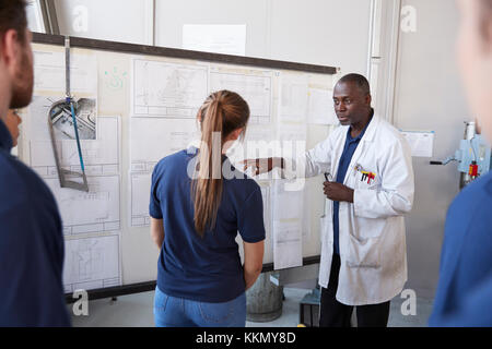 Engineer with apprentice at white board in front of group Stock Photo