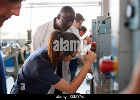 Engineer training female apprentice using a drill press Stock Photo