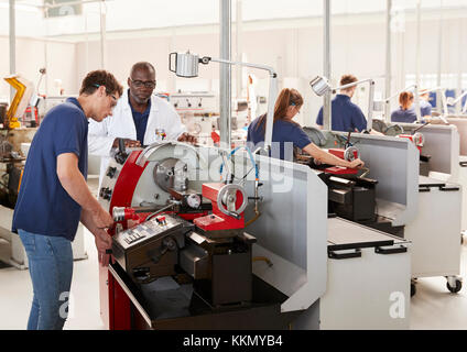 Engineer talking to male apprentice at his workstation Stock Photo