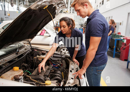 Two apprentice mechanics looking at the engine in a car Stock Photo