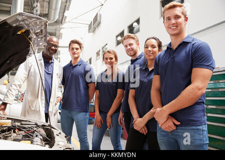 Car mechanic and apprentices in a garage looking to camera Stock Photo