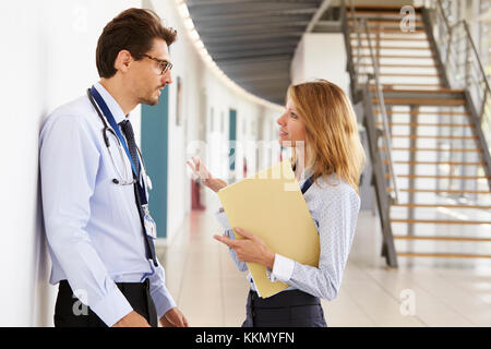 Young male and female doctors discuss notes at meeting Stock Photo