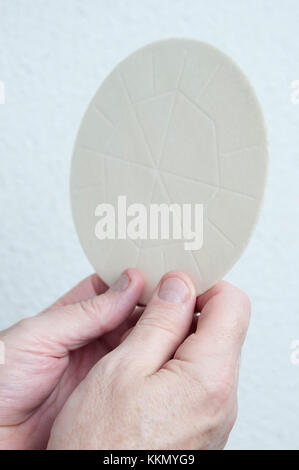 A priests hands holds the host bread that is consecrated in the Eucharist. Part of a church religious communion ceremony or a service. Stock Photo