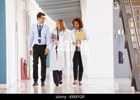 Three young male and female doctors walking in hospital Stock Photo