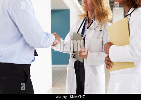 Three male and female doctors shaking hands, mid section Stock Photo