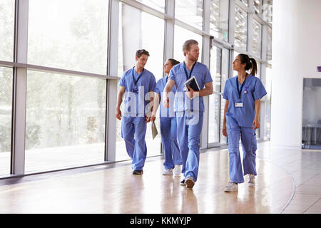 Four healthcare workers in scrubs walking in corridor Stock Photo