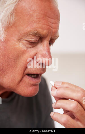 Senior Man Sitting On Bed At Home Taking Medication Stock Photo