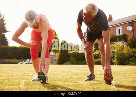 Healthy Senior Couple Exercising In Garden Together Stock Photo