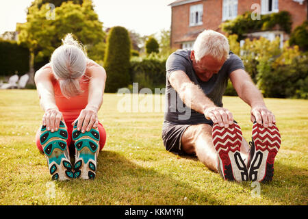 Healthy Senior Couple Exercising In Garden Together Stock Photo