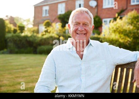 Senior Man Sitting On Garden Bench In Evening Sunlight Stock Photo