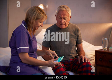 Nurse Helping Senior Man To Organize Medication On Home Visit Stock Photo