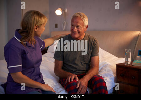 Nurse Talking With Senior Man In Bedroom On Home Visit Stock Photo
