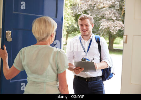 Senior woman opens door to male charity worker doing survey Stock Photo