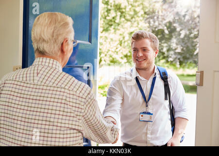 Senior man greeting male care worker making home visit Stock Photo