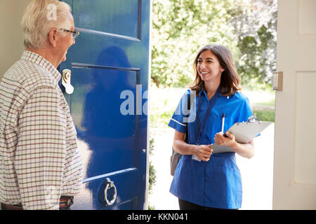 Senior man greeting female nurse making home visit Stock Photo