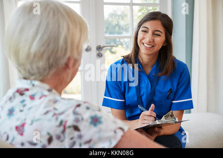 Senior woman sitting at home with care nurse taking notes Stock Photo