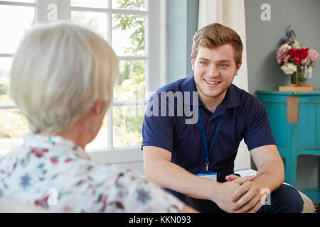 Senior woman talking with male care worker on home visit Stock Photo