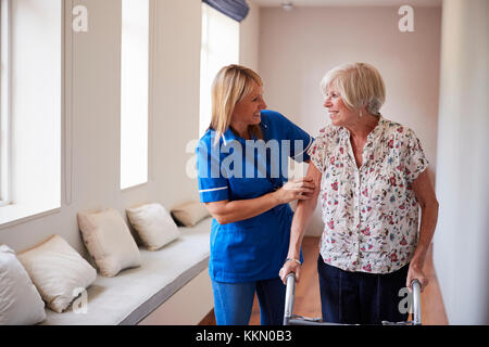 Nurse helping senior woman use a walking frame Stock Photo