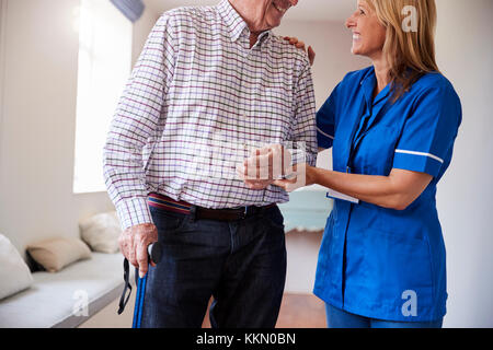 Nurse helping senior man walk using a walking stick Stock Photo